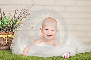 Beautiful blue-eyed baby lying on his tummy , near Easter eggs