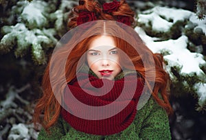 Beautiful blue eyed red haired smiling girl posing in front of snow covered firtrees. Fairytale concept