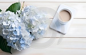 beautiful blue hydrangea flowers and coffee cup on light wooden table for freelancing business card decor