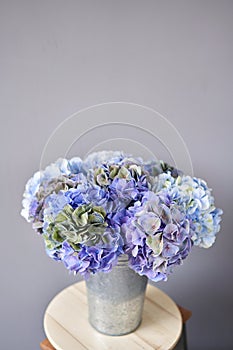 Beautiful blue hydrangea flowers in a vase on a table . Bouquet of light pink flower. Decoration of home. Wallpaper and