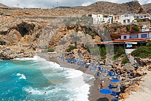 Beautiful blue lagoon with umbrellas at sandy beach, Chora Sfakion town, Crete island