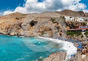 Beautiful blue lagoon with umbrellas at sandy beach, Chora Sfakion town, Crete island