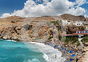 Beautiful blue lagoon with umbrellas at sandy beach, Chora Sfakion town, Crete island