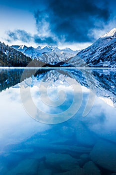 Beautiful blue lake in the mountains. Flat mirror surface of the water under the clouds.