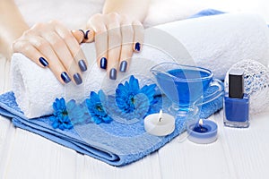 Beautiful blue manicure with chrysanthemum and towel on the white wooden table. spa