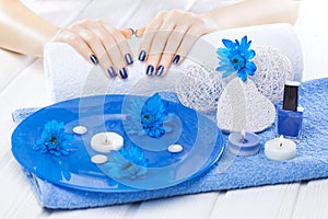 Beautiful blue manicure with chrysanthemum and towel on the white wooden table. spa