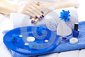 Beautiful blue manicure with chrysanthemum and towel on the white wooden table. spa