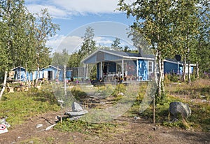 Beautiful blue sami or saami country house at Sitojaure lake shore with birch trees and flower pots. At Kungsleden