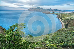 Beautiful blue sea, greenery on the shore and mountains in the background