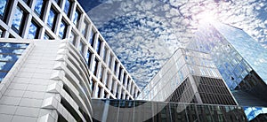 Beautiful blue sky with clouds reflecting in windows, banner design. Low angle view of modern buildings on sunny day