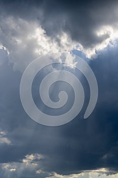 Beautiful vertical cloudscape with sun rays shining through the dark clouds