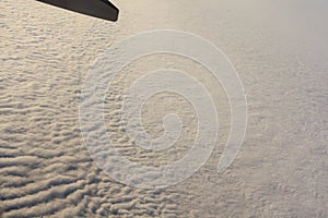 Blue sky with clouds under the wing of an airplane.