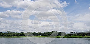 Beautiful blue sky with highway or bridge across river by vehicle, white clouds and green tree