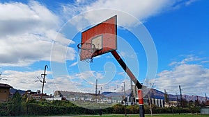 Beautiful blue sky with white clouds, old red rusty basketball hoop in Zenica