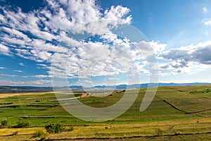 Beautiful blue sky with white clouds over green agricultural fields at summertime