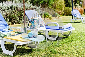 Beautiful blue straw hat on yellow sunbed near pool. Side View. Summer Travel Vacation Concept