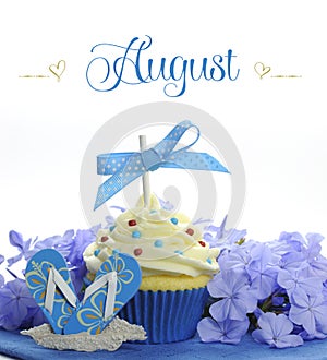 Beautiful blue Summer holiday theme cupcake with seasonal flowers and decorations for the month of August