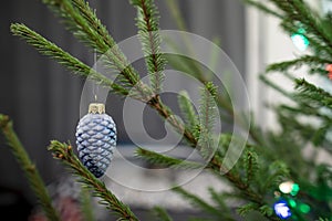 Beautiful blue toy - a bump on a Christmas tree with a garland, on a blurred background of the wall