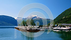 Beautiful boat marina on the fjord at Valldal, Norway on a sunny day with snow on the peaks of the spectacular nearby mountain.