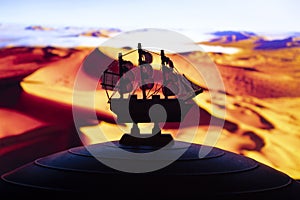 Beautiful boat toy over a blue balll with blurred red and orange desert scene at background