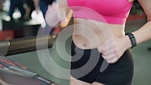 Beautiful body of active lady at workout, sportive woman walking on treadmill