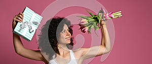 A beautiful body athletic girl with curly hair and in sportswear, holds in a strong muscular arm a bouquet of gentle tulpans