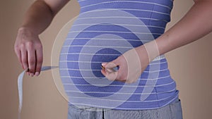 Beautiful body of pregnant woman with measuring tape, mother check unborn baby development at home interior, healthcare
