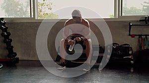 The beautiful body shape of a handsome young man exercising in a fitness center. He is resting tired and drinking water in the gym