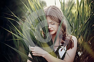 Beautiful boho girl posing in grass at sunset light near lake. a