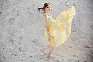 Beautiful boho girl walking on sandy beach at sunset light near