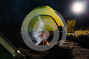Beautiful bonfire and folding chairs near camping tent outdoors at night