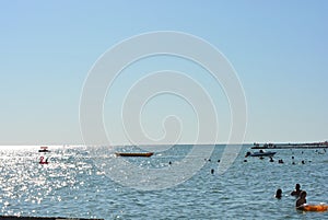 Beautiful border between the blue sky and the black sea with small waves and fine golden and bright reflections of the sun on the