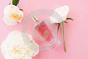 Beautiful bottle of women`s perfume on a pink background with a chic flower of fragrant peony. template for perfume and toilet