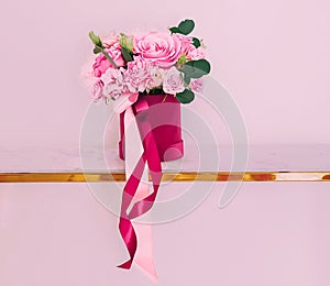 Beautiful bouquet of blooming flowers in flower box on pink background, holiday gift, luxury floral design