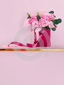 Beautiful bouquet of blooming flowers in flower box on pink background, holiday gift, luxury floral design