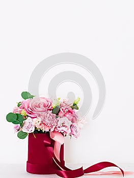 Beautiful bouquet of blooming flowers in red flower box on white background, holiday gift, luxury floral design