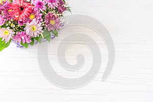 Beautiful bouquet of bright flowers in basket on white wooden background