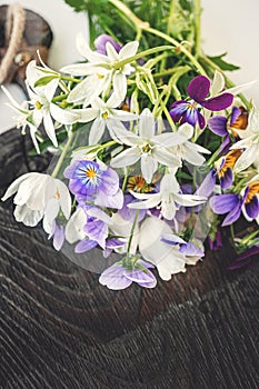 Beautiful bouquet of delicate wild flowers anemones and violets on an old wooden Board. Close-up, selective focus