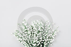 Beautiful bouquet of flowers lily of the valley on pastel table from above. Minimal composition and flat lay style.