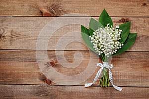 Beautiful bouquet of flowers lily of the valley with ribbon on wooden background