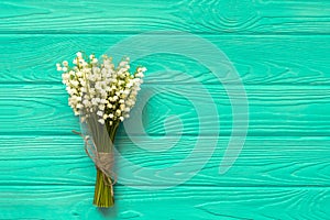 Beautiful bouquet of flowers lily of the valley on turquoise wooden table from above.