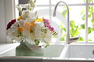 Beautiful bouquet with freesia flowers in kitchen sink