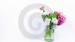Beautiful bouquet of natural fresh flowers appears in a glass jar. White background.