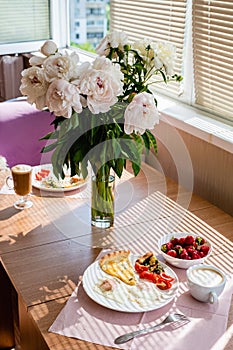 A beautiful bouquet of peonies stands in a vase on the table