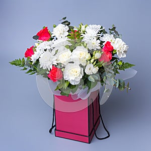 Beautiful bouquet in a pink gift box stands on a blue background.