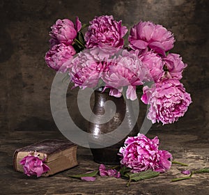 Beautiful bouquet of pink peonies in vase and old book