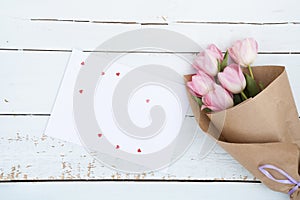 Beautiful bouquet of pink tulips next to a white envelope and pink sugar hearts