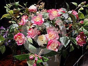 Beautiful bouquet of pink and yellow roses in a white vase on wooden table black marble background, artificial flowers