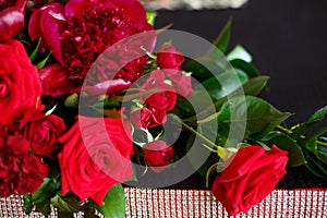 A beautiful bouquet of red roses and peonies is on the table