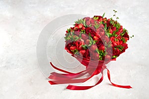 A beautiful bouquet of ripe strawberries and scarlet roses on a gray background